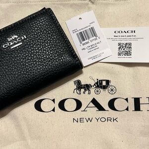 Coach black pebbled leather bifold wallet with silver tone hardware.